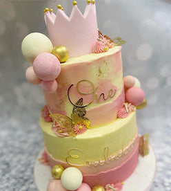2 tier pink and vanilla buttercream birthday cake with a pink crown and balls