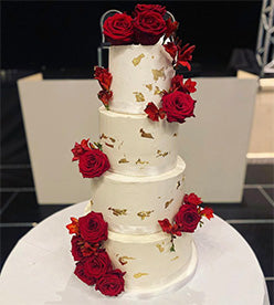 4 tier wedding cake with golf leaf and red roses